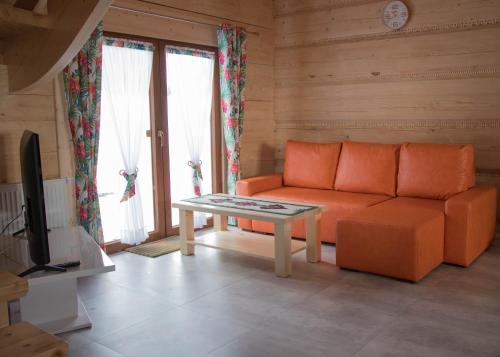 a living room with an orange couch and a table at Dwór Pan Tadeusz in Orawka