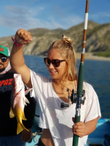 a woman holding a fish on a boat at ChiloChill Glamping Resort in La Ventana