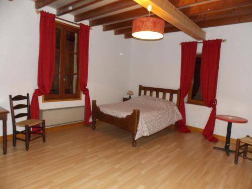 1 dormitorio con 1 cama con cortinas rojas y suelo de madera en Gîte l'Antre Vous en Saint-Philippe-dʼAiguille