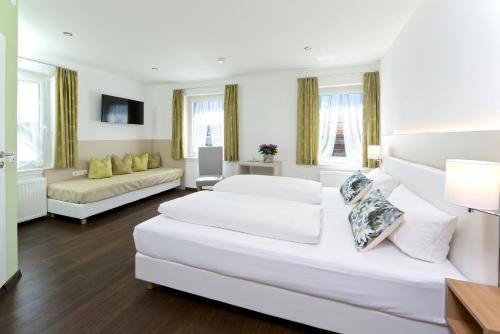a large white room with two beds and a couch at Hotel Bayerischer Hof in Lindenberg im Allgäu