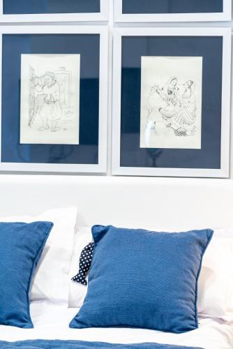 a white bed with blue pillows and two pictures at Dar Indigo in Sidi Bou Saïd