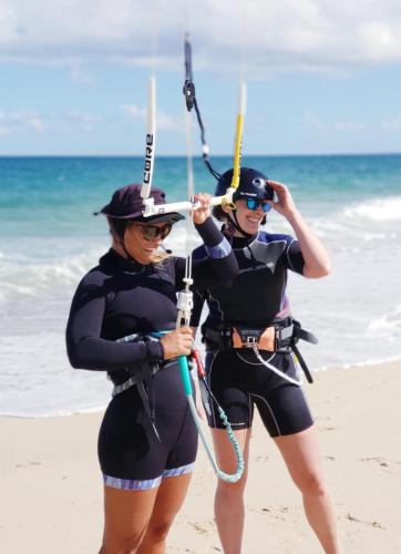 two women in wet suits standing on the beach at ChiloChill Glamping Resort in La Ventana