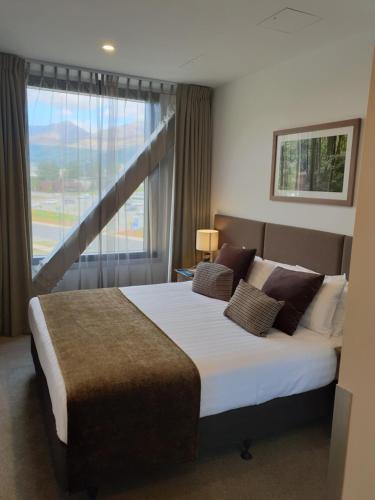 a bedroom with a large bed with a large window at Wyndham Garden Remarkables Park Queenstown in Queenstown