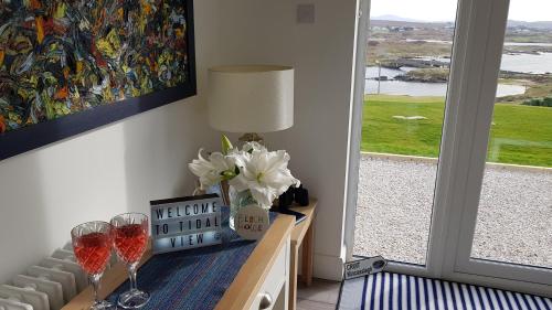 a table with two wine glasses and a vase of flowers at Tidal View in Kincasslagh