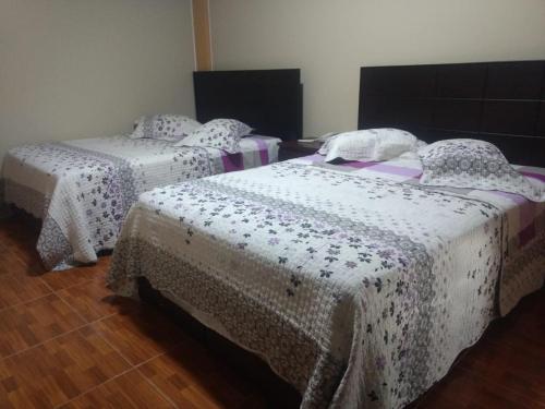 two beds in a room with white sheets at Gran Hotel Virrey in San Ramón