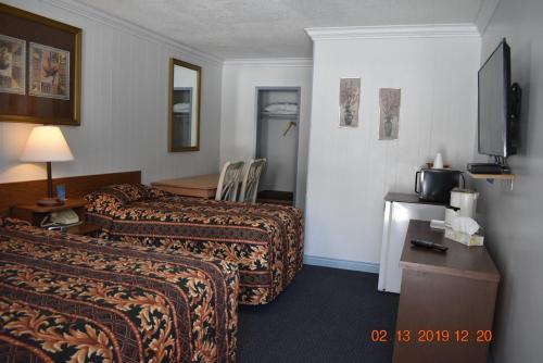 a hotel room with two beds and a table at Evening Star Motel in Greenwood