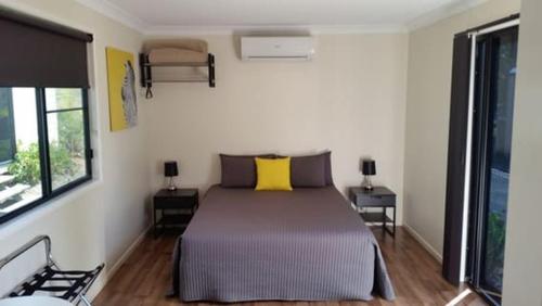 a bedroom with a bed with two tables and two windows at Augathella Palms Motel in Augathella