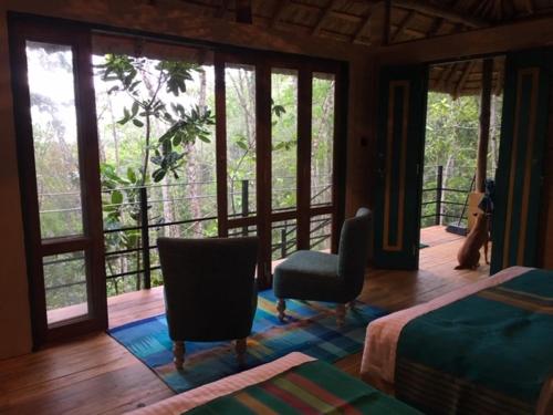 a bedroom with a bed and two chairs and windows at Rambas Reserve in Avissawella