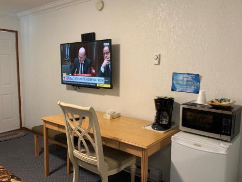 a room with a table with a television on the wall at Evening Star Motel in Greenwood