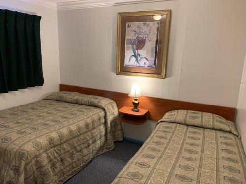 a hotel room with two beds and a lamp on a table at Evening Star Motel in Greenwood