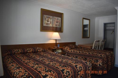 a hotel room with two beds and a table at Evening Star Motel in Greenwood