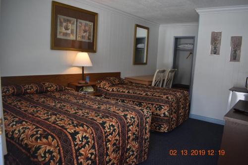 a hotel room with two beds and a table at Evening Star Motel in Greenwood