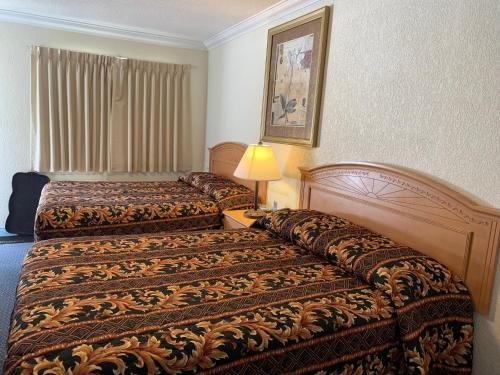 una habitación de hotel con 2 camas y una lámpara en Evening Star Motel, en Greenwood