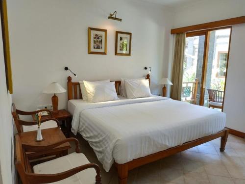 Un dormitorio con una gran cama blanca y una ventana en Puri Mesari Hotel en Sanur