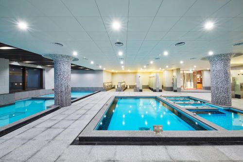 - une grande piscine d'eau bleue dans un bâtiment dans l'établissement Pyeongchang Ramada Hotel & Suite by Wyndham, à Pyeongchang