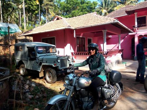 a woman sitting on a motorcycle in front of a house at Spice Garden Farm house in Sultan Bathery
