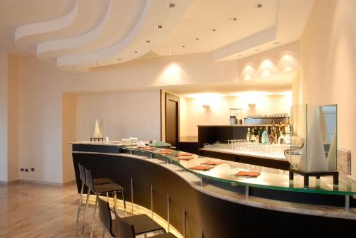 a restaurant with a long bar with stools at San Giorgio, Sure Hotel Collection by Best Western in Forlì