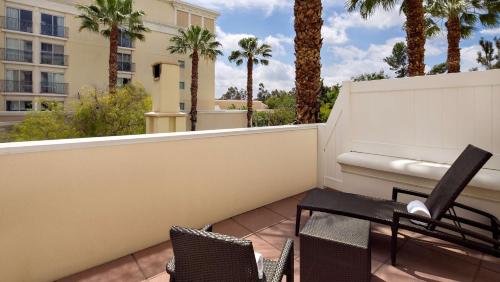 a balcony with two chairs and a fence with palm trees at Hyatt Regency Valencia in Valencia