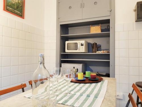 a kitchen with a table with wine glasses and a microwave at Medieval Pieve, holiday home with garden, WiFi & parking in Pieve di Teco