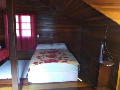 1 dormitorio con 1 cama en una habitación de madera en Casa Maringá, en Visconde De Maua