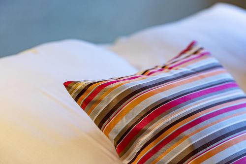a close up of a striped pillow on a bed at The Originals City Hotel de l Ange Guebwiller in Guebwiller