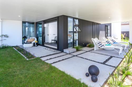 a patio with white chairs and grass at Waters Edge B&B in Whitianga