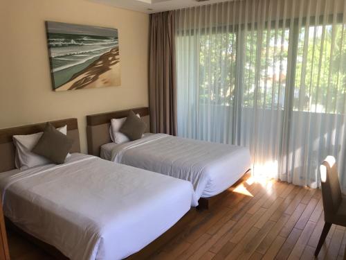 2 camas en una habitación de hotel con ventana en Villas at Da Nang Beach Resort,3 Bedrooms Garden View, en Da Nang