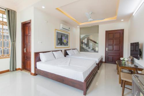 a bedroom with two beds and a desk at Luna Rossa Villa in Hoi An