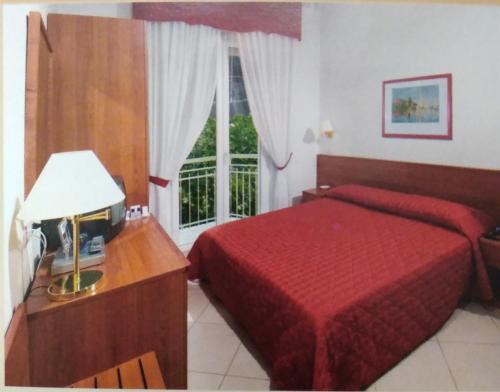 una camera d'albergo con letto rosso e finestra di ALBERGO METAURO a Fano
