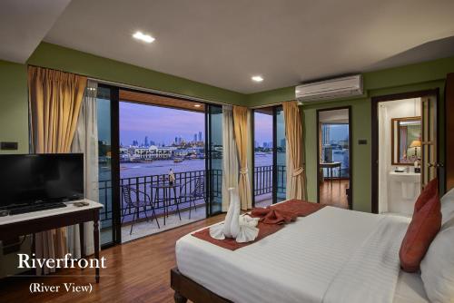 een slaapkamer met een bed, een televisie en een balkon bij Baan Wanglang Riverside, Bangkok in Bangkok