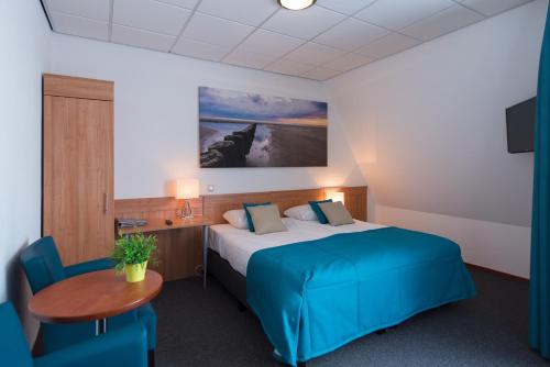 a hotel room with a bed and a table at Hotel Nes in Nes