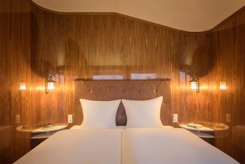 a bedroom with a large white bed with wooden walls at Villa Lotsenhäuser Rügen - Luxus Ferienhaus - 3 Schlafzimmer - Sauna - Dachterrasse mit Boddenblick in Breege