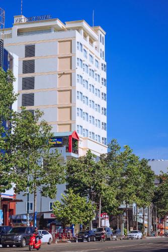 a tall white building on a city street with cars at Victory Hotel Tây Ninh in Tây Ninh