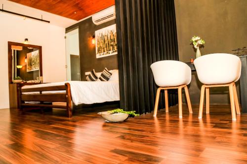 two white chairs sitting in a room with a bed at Eden Studio Apartments - 1 in Colombo