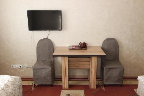 a table with two chairs and a television on a wall at Madanur Hotel in Karakol
