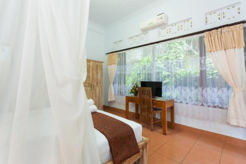 a bedroom with a bed and a desk and a window at Ani's Villas in Ubud