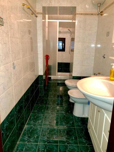 a green tiled bathroom with two toilets and a sink at La Residenza dei Papi in Papigno