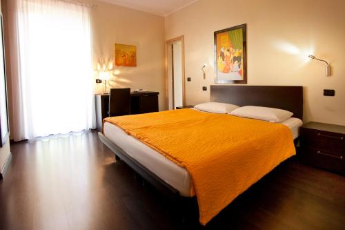 a bedroom with a large bed with an orange blanket at Hotel Villa Smeralda in Malcesine
