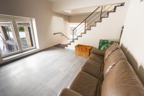 a living room with a couch and a staircase at Vakantiewoning Ter Luyghem in Houthulst