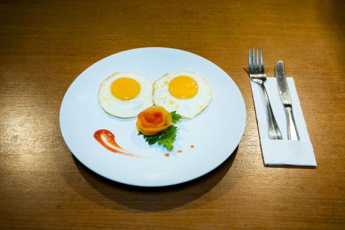 a white plate with eggs and sausage on a table at Ani's Villas in Ubud