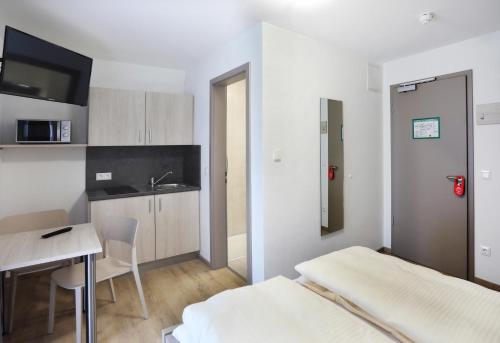 a bedroom with a bed and a table and a kitchen at Apartment Hotel 37 in Landshut