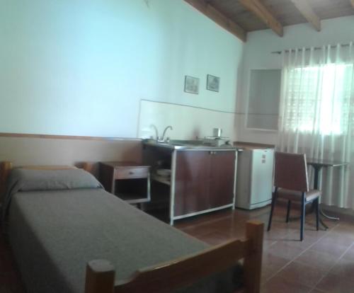 een slaapkamer met een bed en een keuken met een wastafel bij Monoambientes Low Cost in Villa Cura Brochero