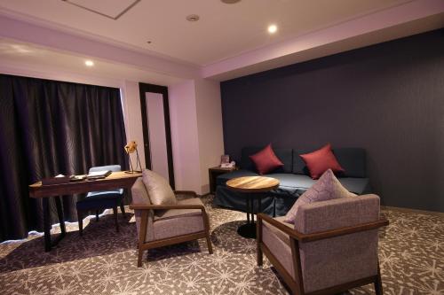 a hotel room with a bed and a desk and chairs at Quintessa Hotel Sapporo in Sapporo