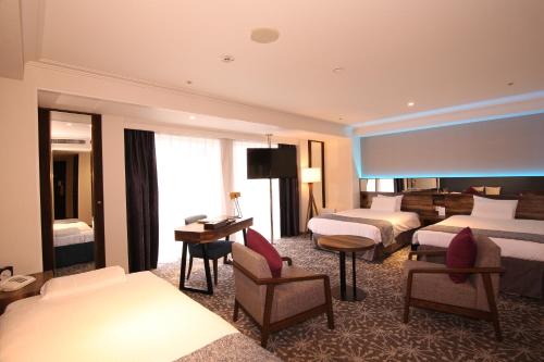 a hotel room with two beds and a television at Quintessa Hotel Sapporo in Sapporo