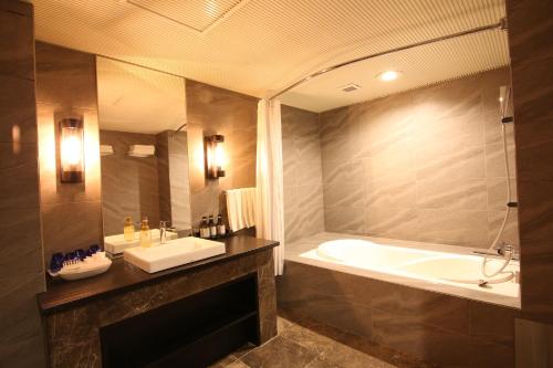 a bathroom with a tub and a sink and a bath tub at Quintessa Hotel Sapporo in Sapporo