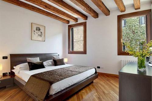 ein Schlafzimmer mit einem großen Bett und zwei Fenstern in der Unterkunft Salmaso Apartments in Venedig