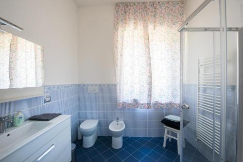 La salle de bains est pourvue de carrelage bleu, de toilettes et d'une douche. dans l'établissement I Gelsomini, à Sienne
