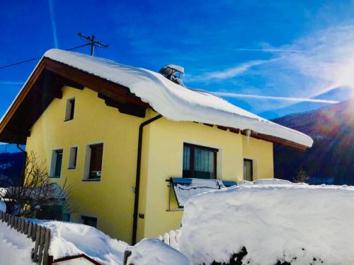una casa amarilla con nieve en el techo en Haus Alpenrose, en Trins