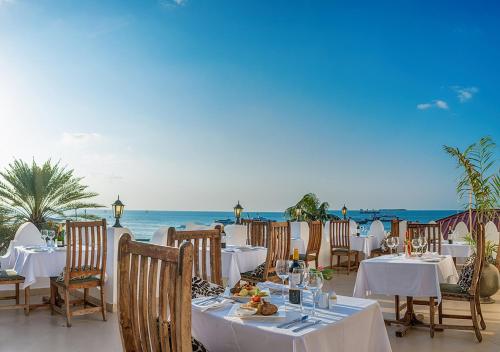 a restaurant with tables and chairs on the beach at The Seyyida Hotel and Spa in Zanzibar City
