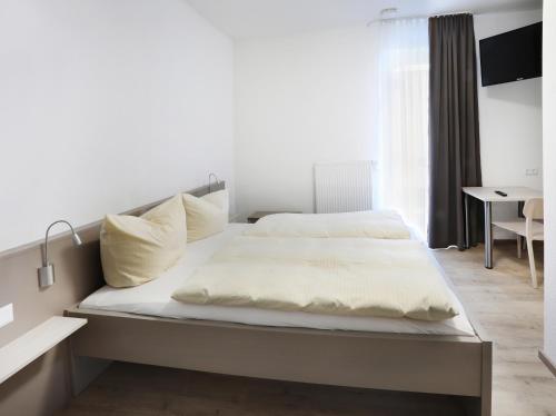 - un lit avec des draps et des oreillers blancs dans une chambre dans l'établissement Apartment Hotel 37, à Landshut